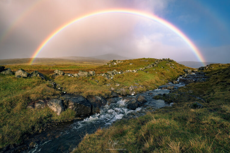 Rainbow over the island of Vagar on the Faroe Islands with an idyllic stream