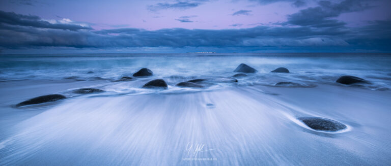 Beach with stones in spray in winter on the Lofoten Islands