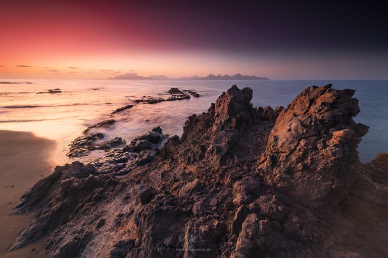 Morning view from the Cape Verde island of Santo Antao towards the island of Sao Vicente in the background with lava rocks in the foreground.