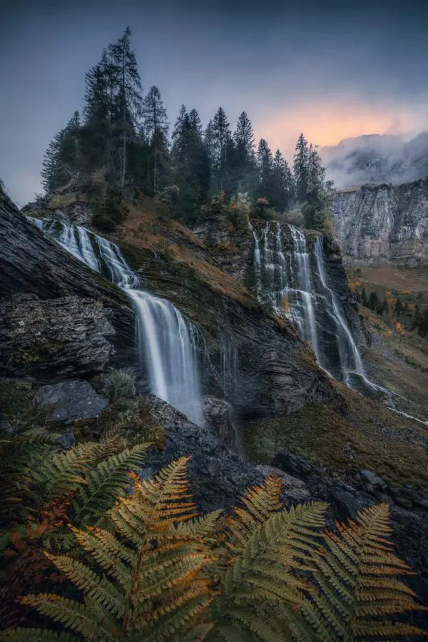 Cascade de la Pleureuse in the magical autumn light in the French Alps with a wide view into the autumnal valley for the morning atmosphere