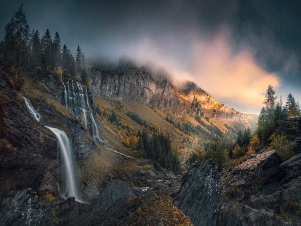 Cascade de la Pleureuse in the magical autumn light in the French Alps with a wide view into the autumnal valley for the morning atmosphere