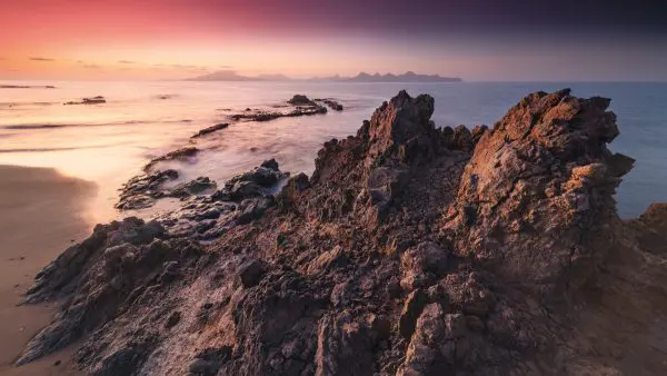 Morning view from the Cape Verde island of Santo Antao towards the island of Sao Vicente in the background with lava rocks in the foreground.