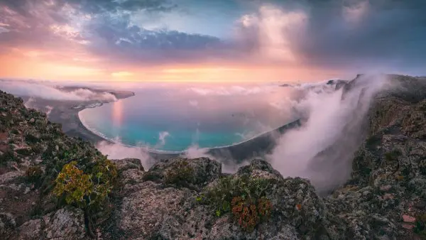 Epischer Blick über die Klippen von Famara auf den Kanaren /Lanzarote) zum farbenfrohen Sonnenuntergang mit malerischer Wolken-Nebel-Stimmung