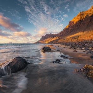 The long Playa de Famara on Lanzarote in the warm light of the sunset