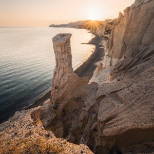 Beach with stone pillar at sunset in the south of the Greek island of Santorini