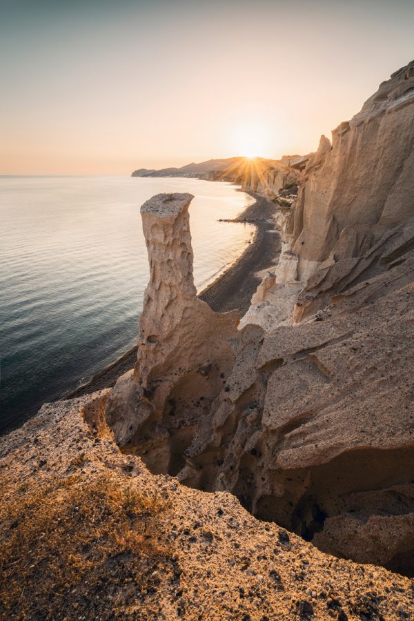 Beach with stone pillar at sunset in the south of the Greek island of Santorini