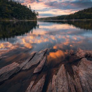 Swedish lake in the south of the country with strong rock structures in the foreground at sunset